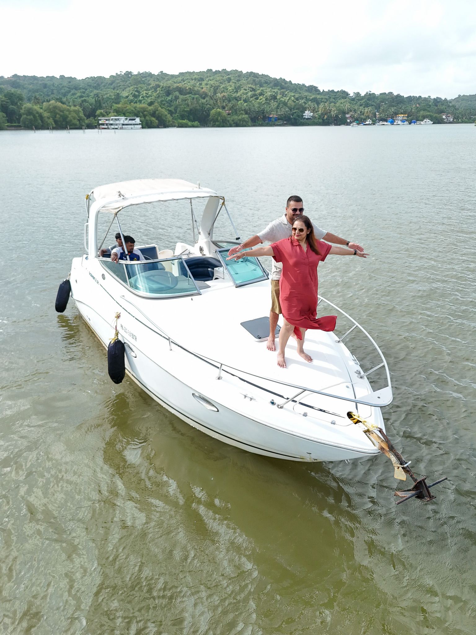 Aerial view of a person standing on the bow of a white motor boat on calm river water